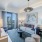 Two-Bedroom Apartments In Atlanta, GA - Mira At Midtown Union - Living Room With Luxury Vinyl Plank Flooring, Area Rug, Couch, Stools, Coffee Table, End Tables With Lamps, Armchair, Large Window, And Glass Door Leading To Balcony.